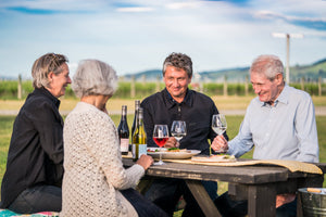 Four people sharing Tiki wines at a picnic table beside the vines in Waipara, North Canterbury