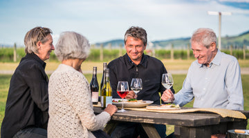 Four people sharing Tiki wines at a picnic table beside the vines in Waipara, North Canterbury